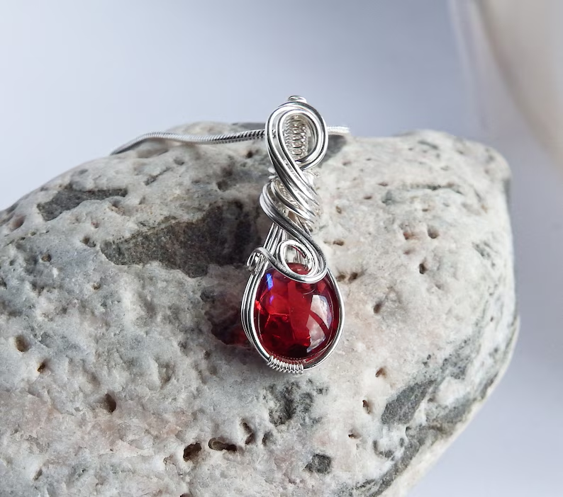 red wire wrapped pendant on a rock