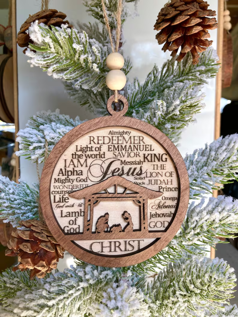 wood christmas ornament with a manger scene and words describing jesus
